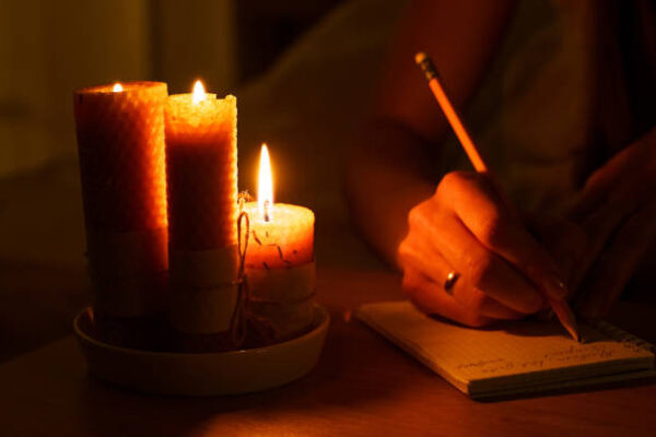 A Woman with lite Candles Writing Her Emotions on A Piece of Paper. How to Cast a Love Spell at Home