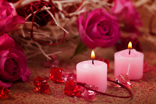 A pink candle surrounded by rose petals and crystals for powerful love spells that work fast.