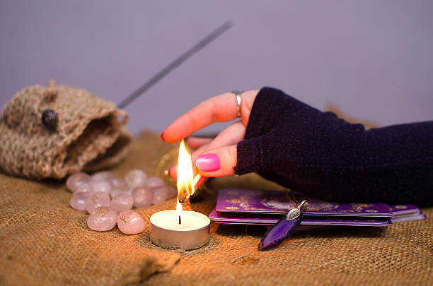A little witch burning a candle, having cards and crystal on their alter