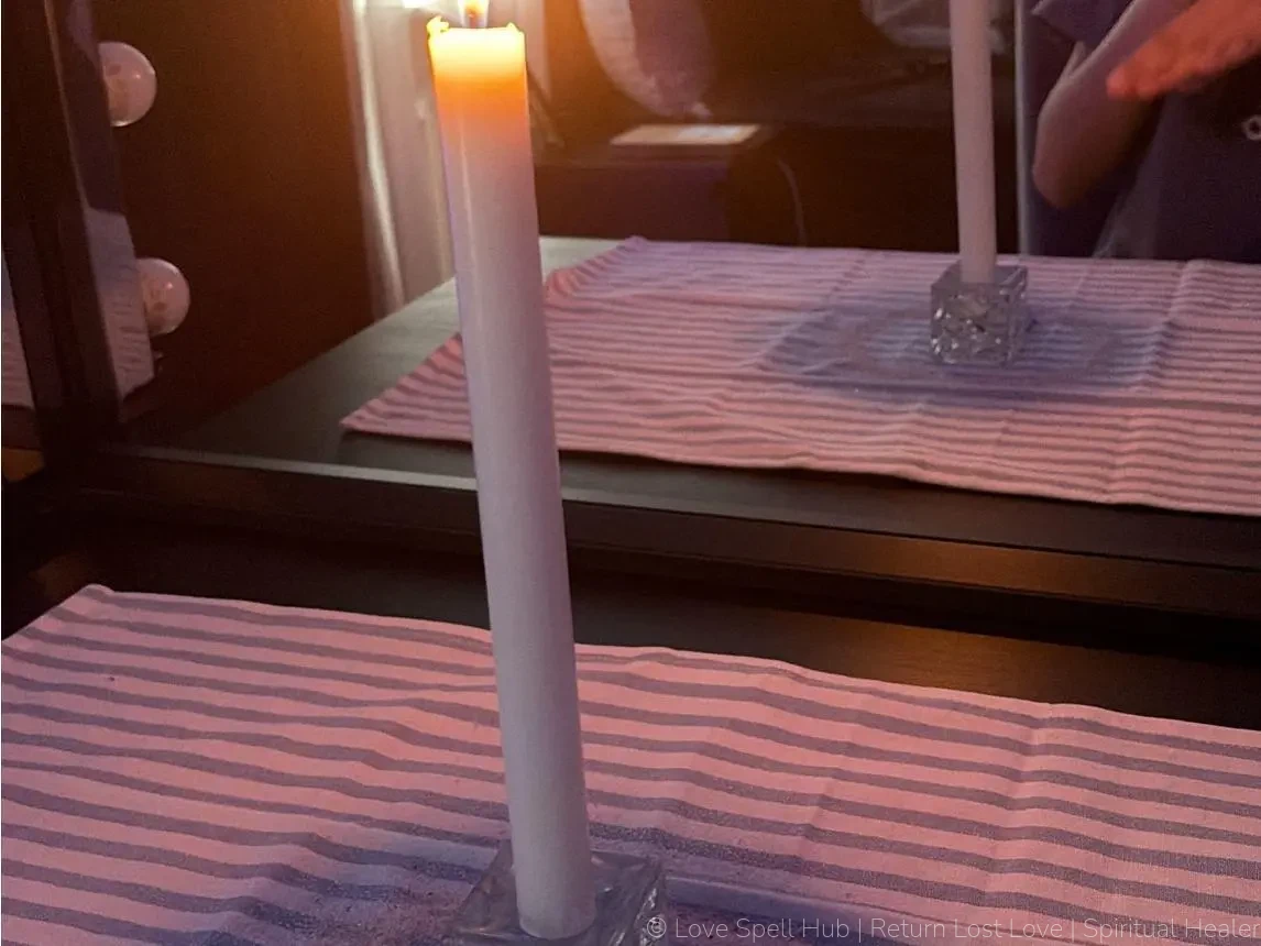A burning white candle and defensive mirror work used for mirror spells to reflect negativity