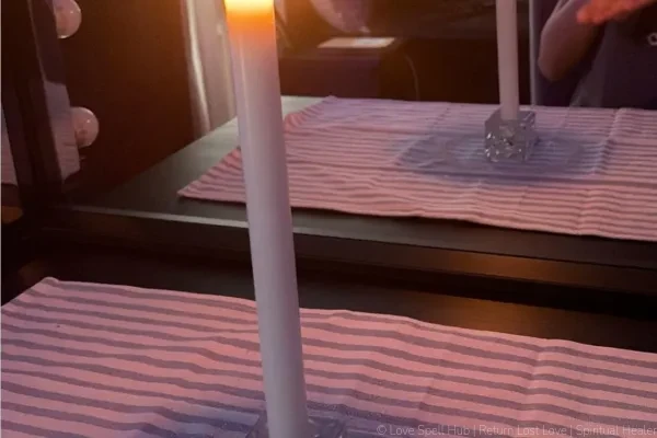 A burning white candle and defensive mirror work used for freezer spells